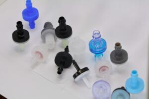 Assorted plastic medical connectors and caps scattered on a white surface.