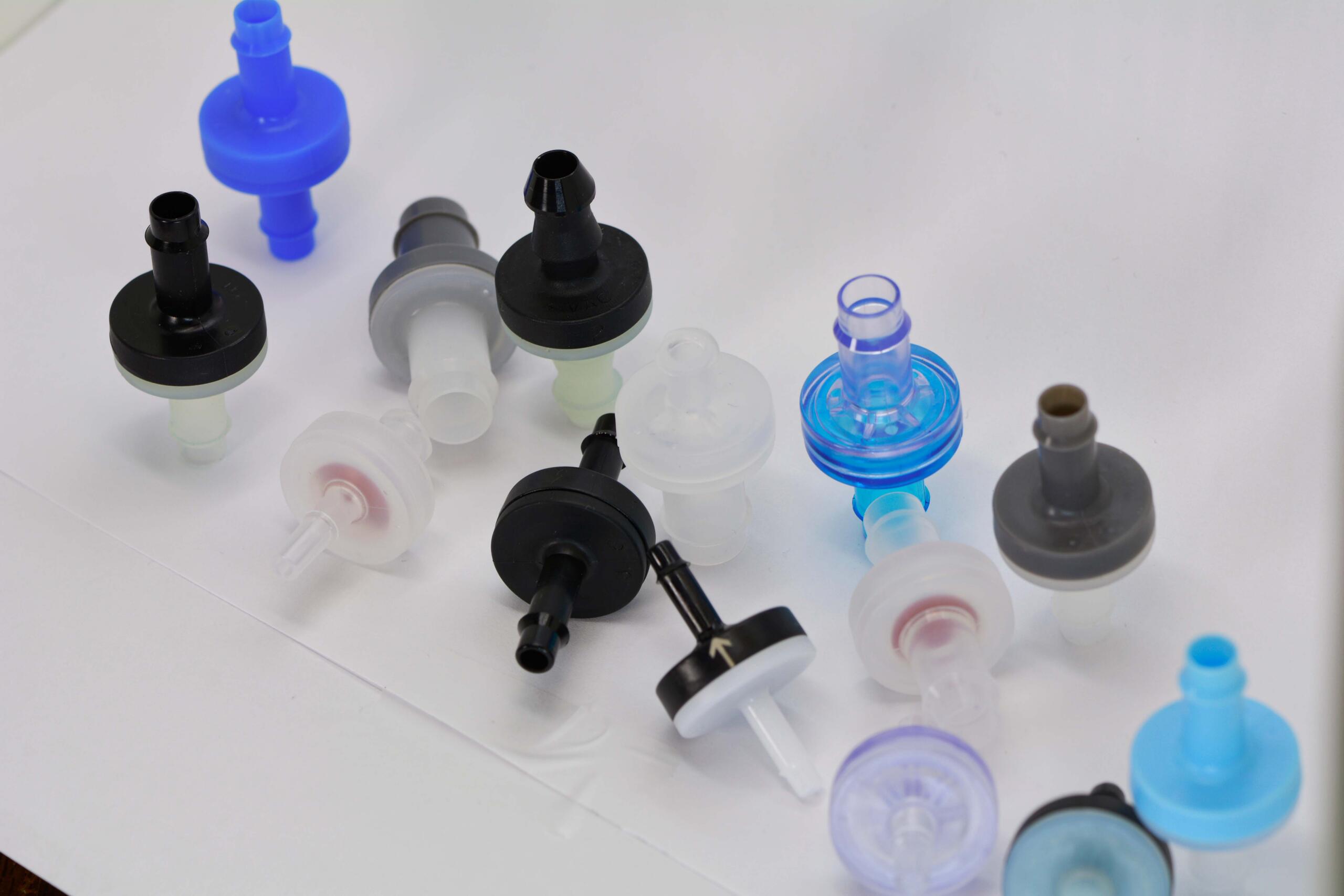 Assorted plastic medical connectors and caps scattered on a white surface.
